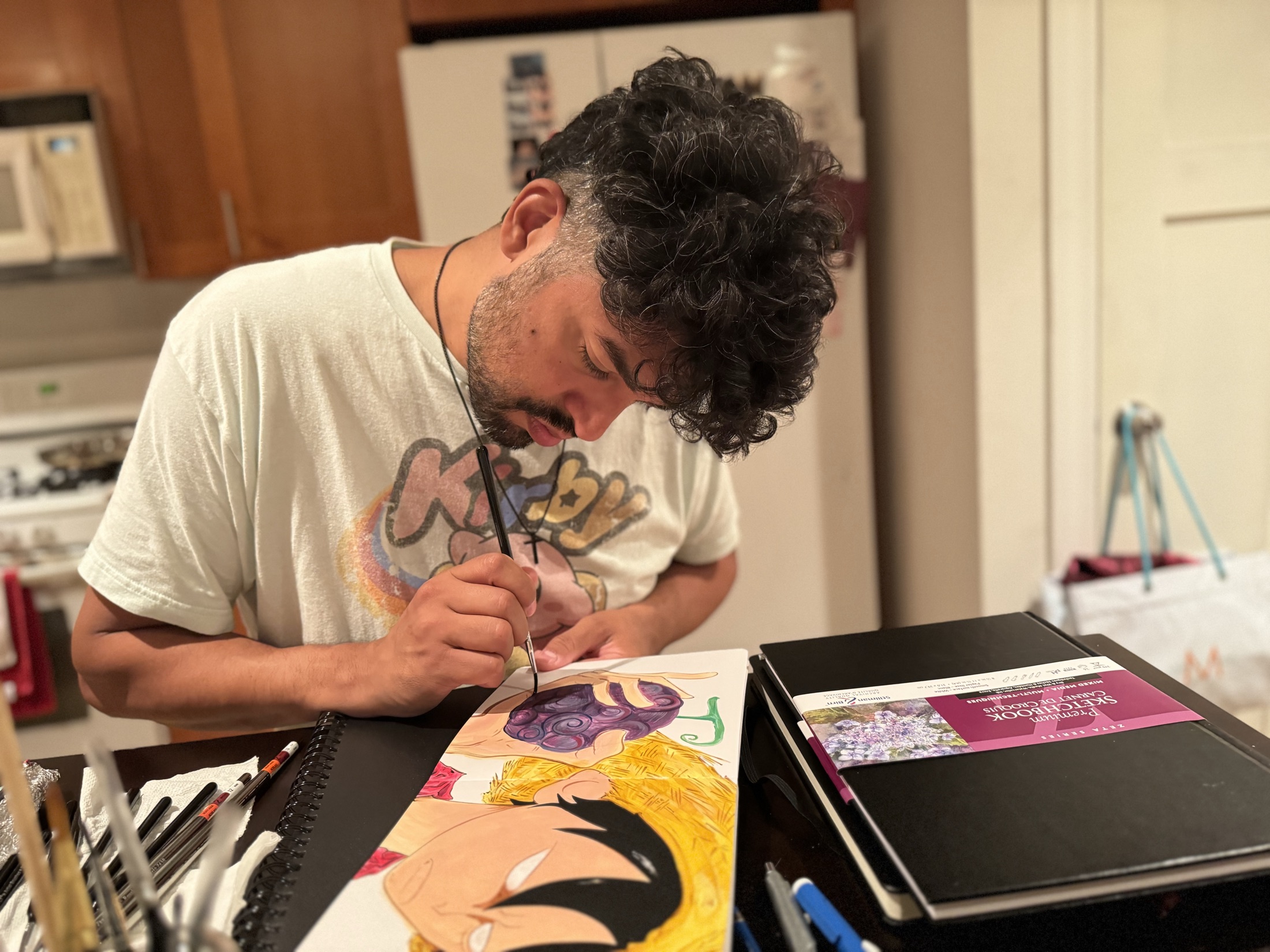 Alfredo Gomez drawing in a sketchbook at his worktable
